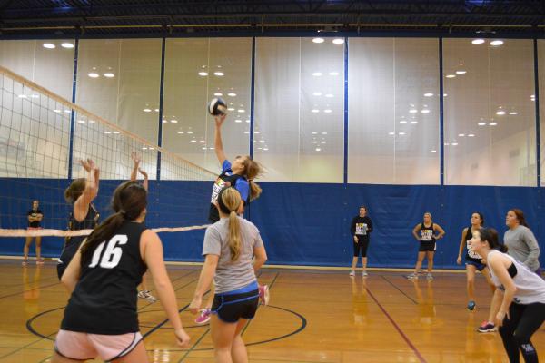 6 on 6 Volleyball game action shot featuring one team attempting an attack and the other team attempting to block the attack