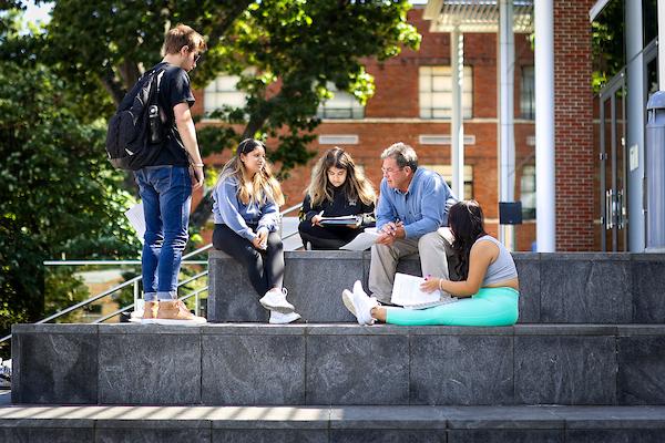 A group of five students sitting on steps talking