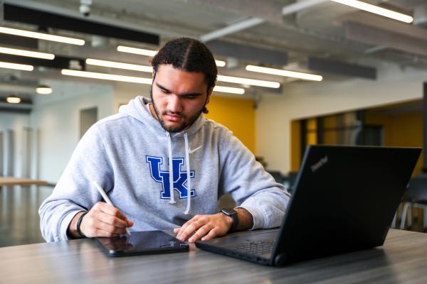 Student writing and working at laptop