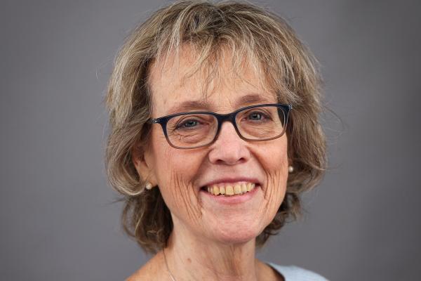 Headshot of a person with short blonde hair, wearing dark rimmed glasses.