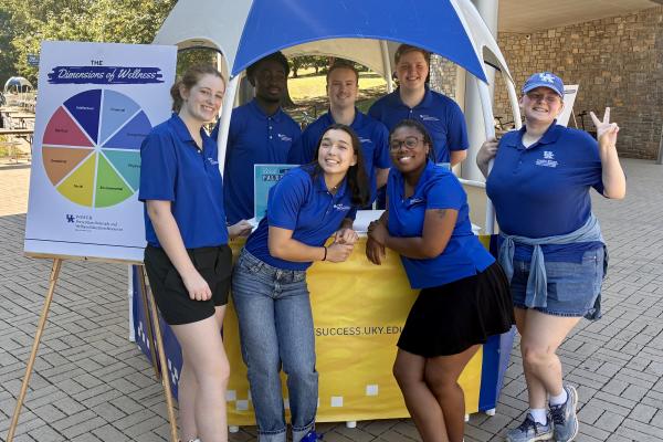 A group of students smiling around a blue and yellow hut