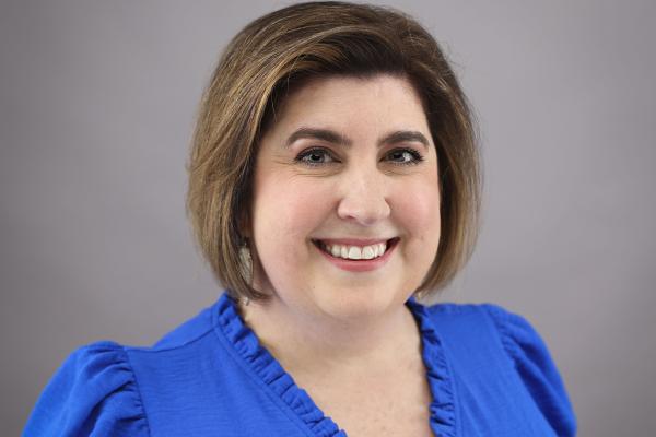 Headshot of a woman with short brown hair wearing a blue short sleeved shirt.