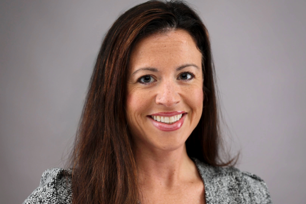Headshot of a female with long brown hair wearing a short sleeved black and white blouse.