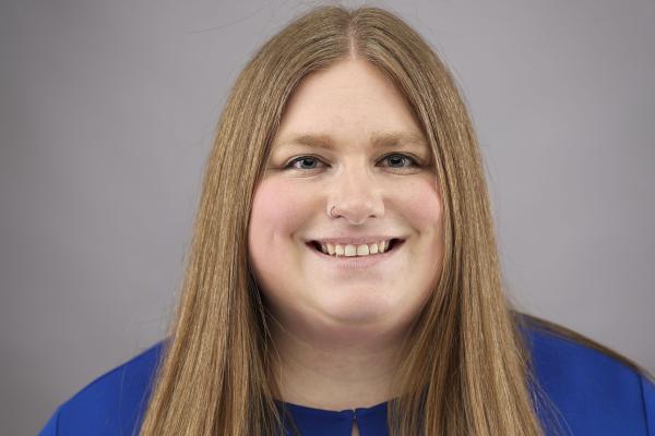 An image of a woman smiling with long blonde hair and wearing a blue shirt.