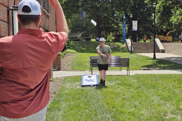 Cornhole game outside of Alumni Gym
