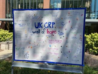 A photograph of the UK CRP Wall of Hope; a large piece of poster board with encouraging messages written by students to any student in recovery who may need it. Messages are written in different colors, and the wall is decorated with stickers.