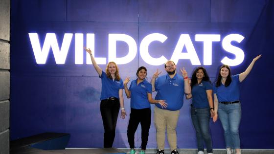 5 students standing in front of a light up sign that says 'Wildcats'