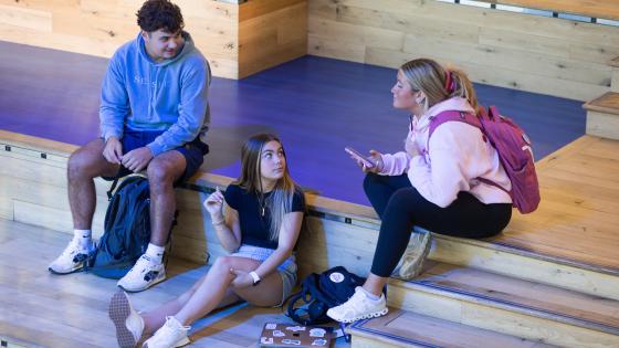 Three students sitting on a staircase talking