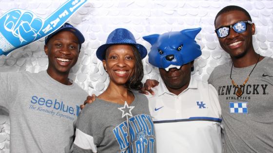 family of 4 dressed in UK branded clothing holding a foam finger and wearing hats