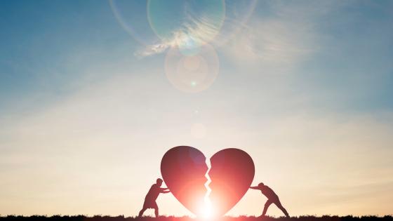 Two people push together the giant pieces of a broken heart