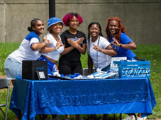 Zeta Phi Beta members pose behind a booth.