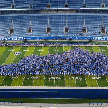 Thousands of students wearing blue arranged in the outline of the state of Kentucky on Kroger Field