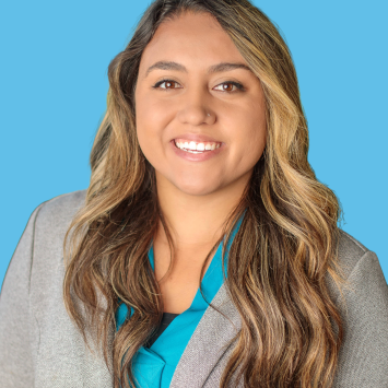 Woman with long brown and golden hair. Pale Blazer with teal button down shirt. 