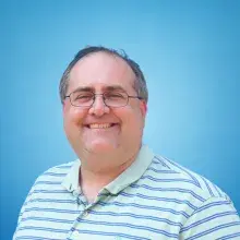 Male with short gray and black hair in a striped polo