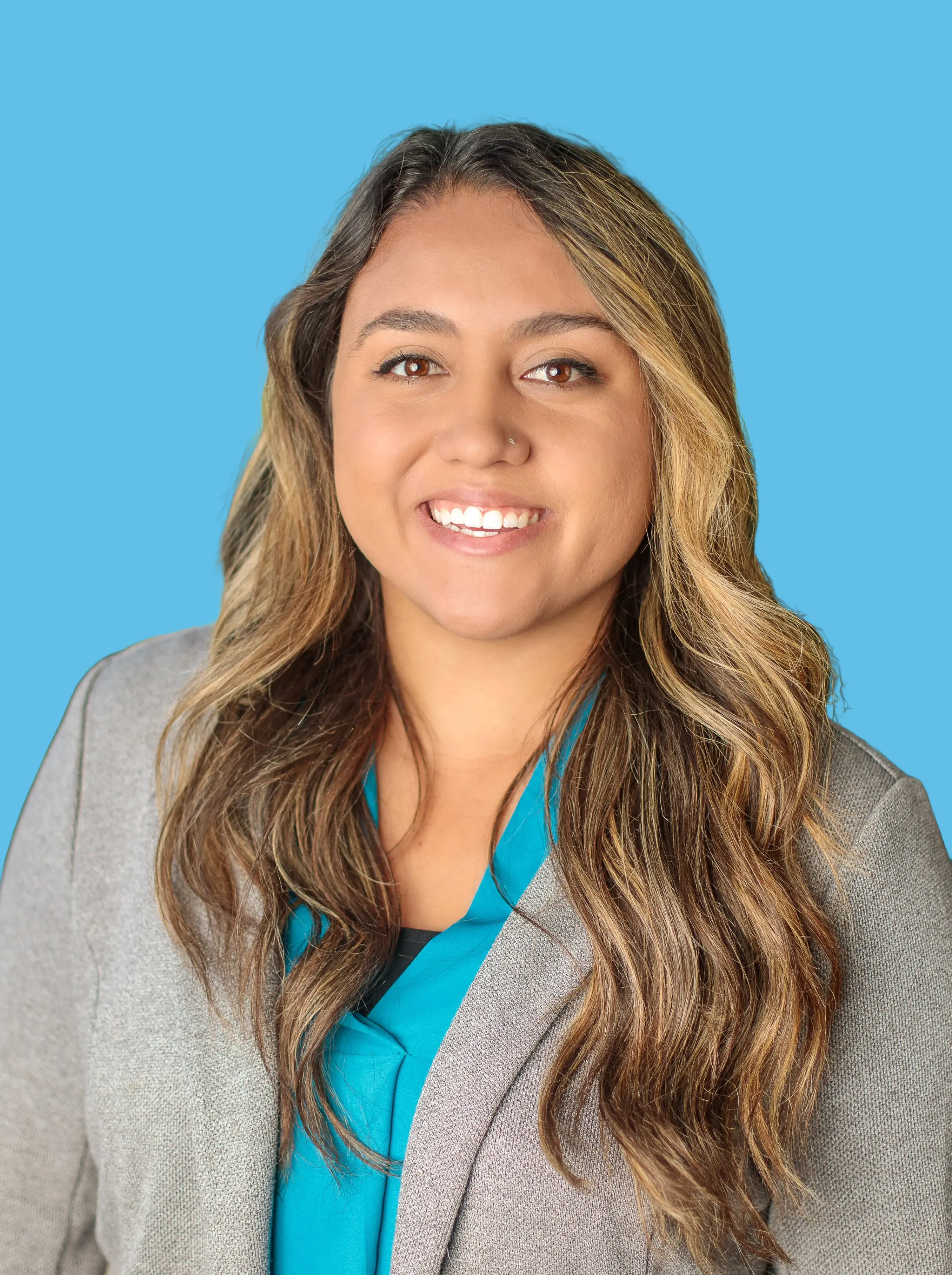 Woman with long brown and golden hair. Pale Blazer with teal button down shirt. 