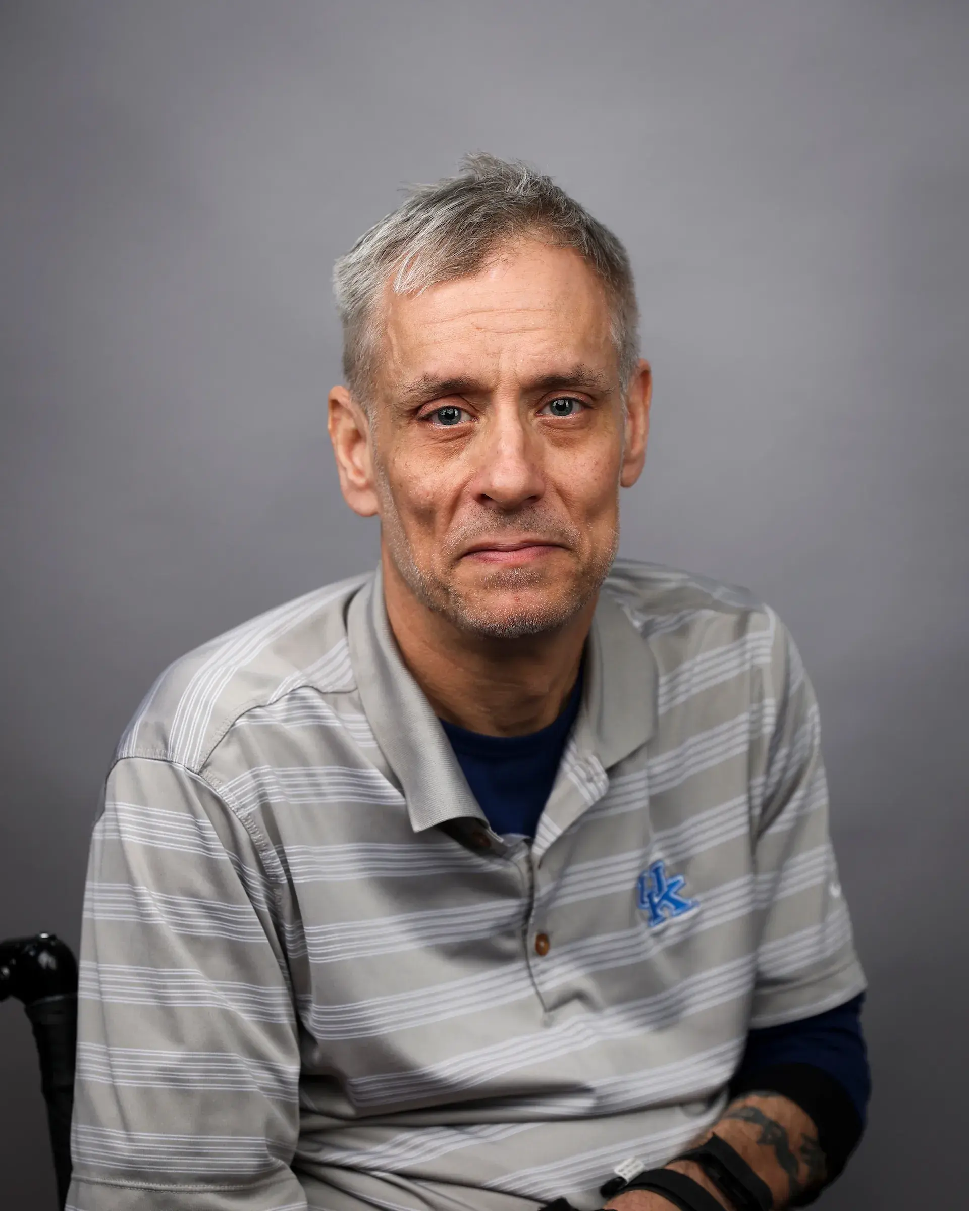 Headshot of a person wearing striped gray and white polo with short, gray hair.