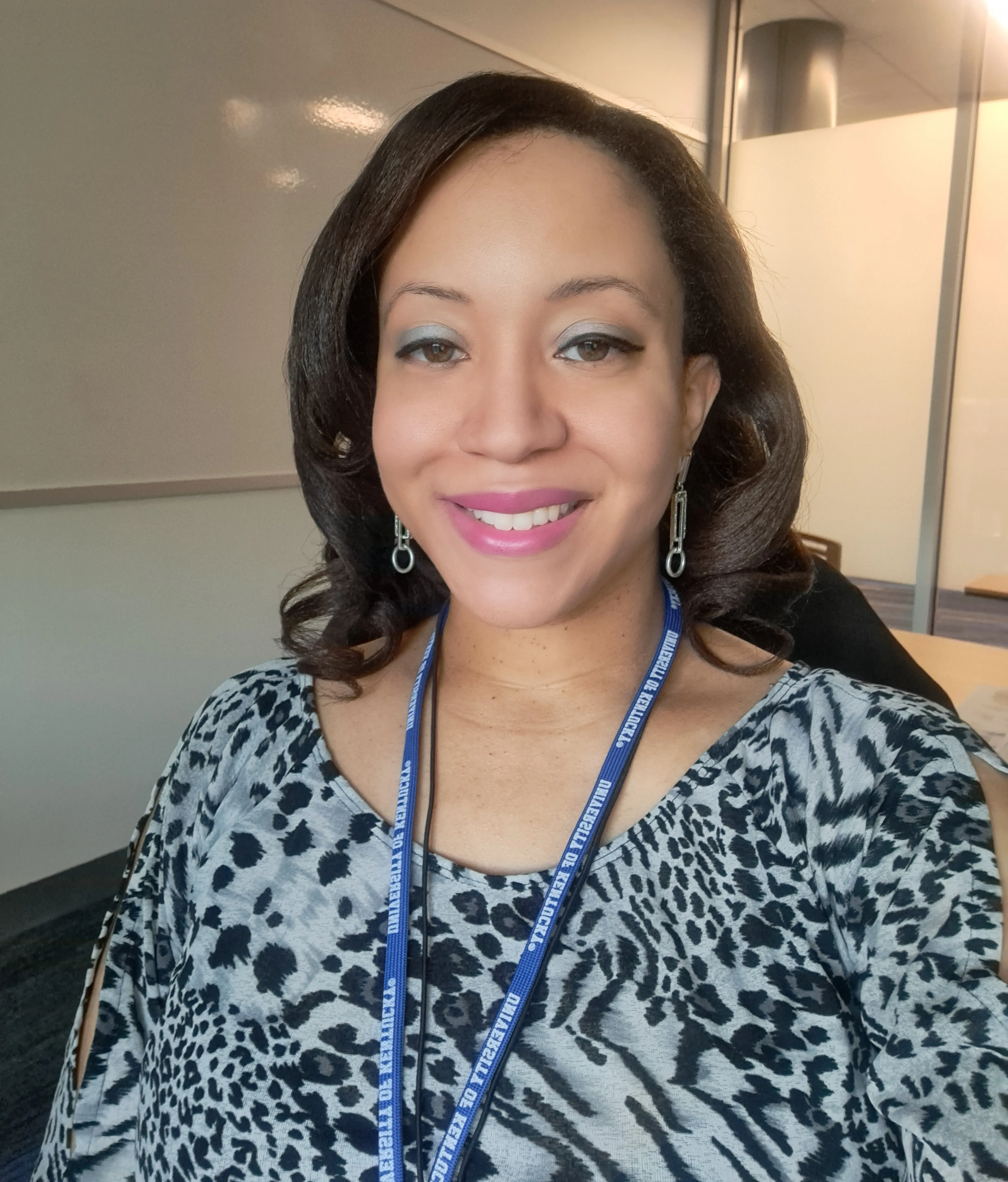 An African American woman with long brown hair smiles at the camera